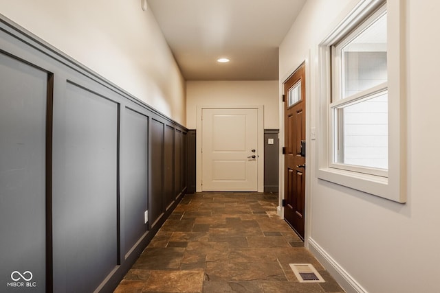 corridor featuring recessed lighting, visible vents, baseboards, and stone finish floor