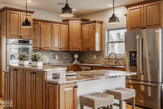 kitchen with tasteful backsplash, a center island, brown cabinets, stainless steel appliances, and a sink