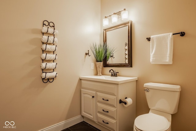 half bath featuring tile patterned flooring, toilet, vanity, and baseboards