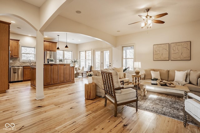 living area with a ceiling fan, recessed lighting, light wood-style floors, and arched walkways