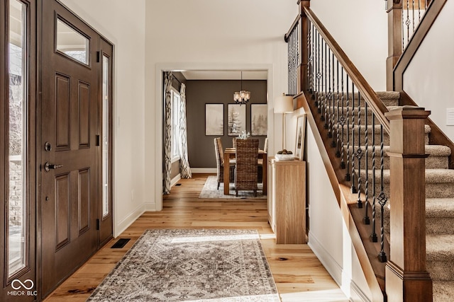 entryway with visible vents, baseboards, a chandelier, and light wood finished floors