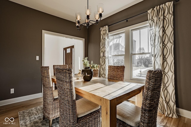 dining area featuring baseboards, an inviting chandelier, and wood finished floors