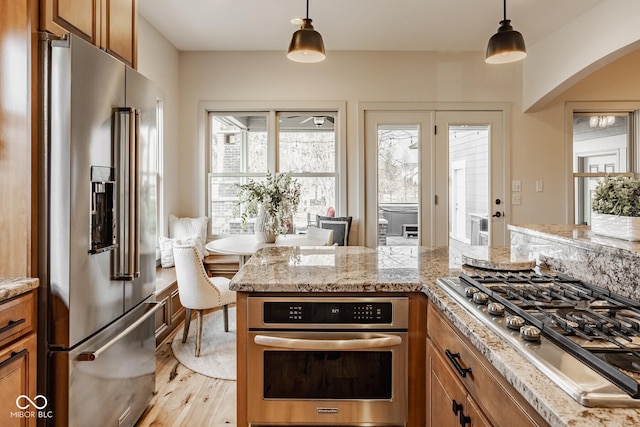 kitchen featuring stainless steel appliances, brown cabinets, and light wood finished floors