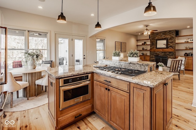 kitchen featuring light wood-type flooring, stainless steel appliances, and arched walkways