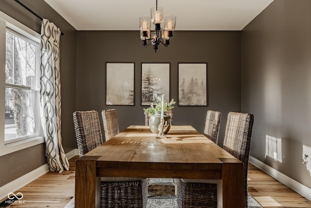 dining area with a notable chandelier, baseboards, and light wood-type flooring