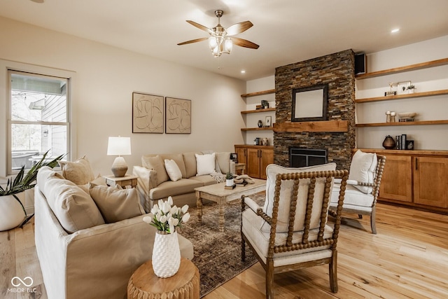 living area featuring a stone fireplace, recessed lighting, a ceiling fan, and light wood-style floors