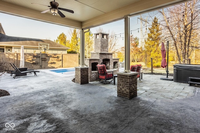 view of patio with ceiling fan, fence, an outdoor brick fireplace, and a hot tub