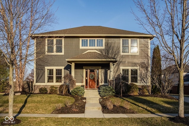 view of front of home featuring brick siding, a shingled roof, and a front lawn