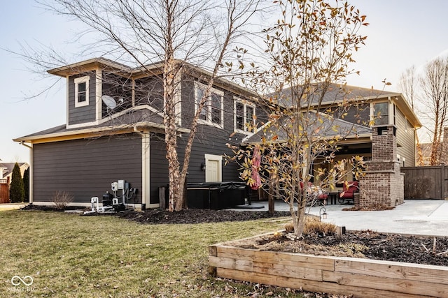 rear view of house with a yard, a patio, fence, and a hot tub