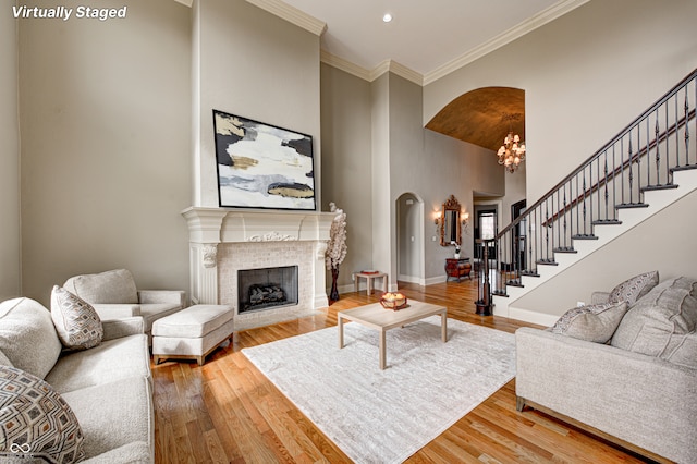 living room with ornamental molding, wood finished floors, stairway, baseboards, and a tile fireplace