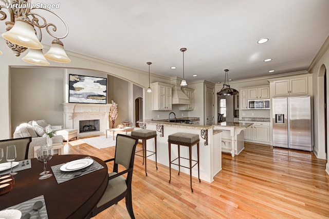 dining room with crown molding, light wood-style flooring, a fireplace, and arched walkways