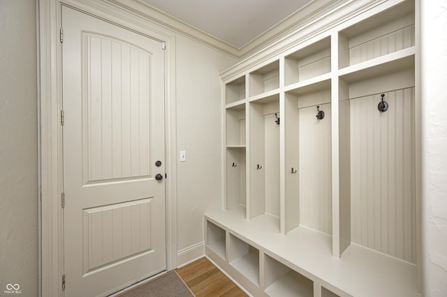 mudroom with crown molding and wood finished floors