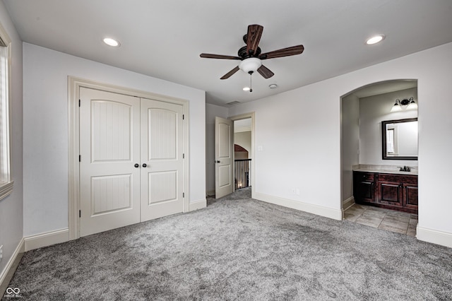 unfurnished bedroom with light carpet, recessed lighting, and arched walkways