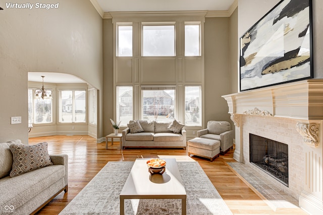 living room with light wood-style flooring, crown molding, and a tiled fireplace