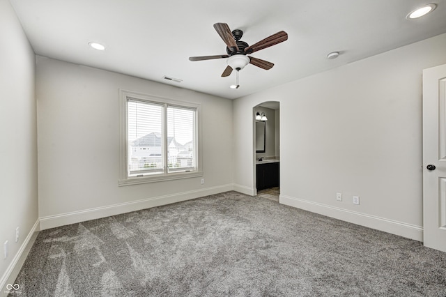 unfurnished bedroom with carpet, visible vents, arched walkways, and baseboards