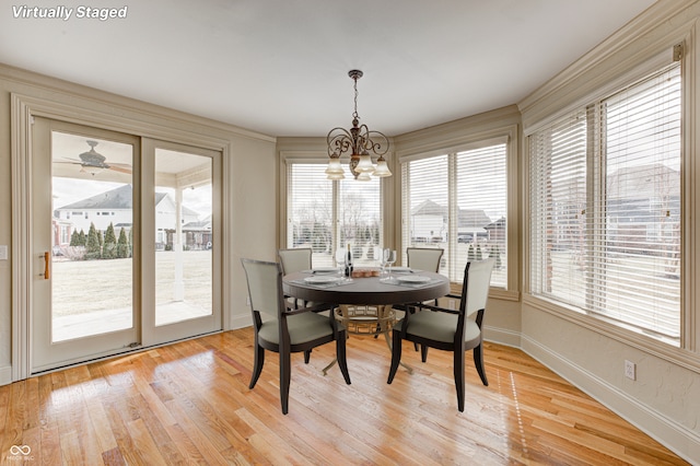 dining area featuring light wood-style flooring, a notable chandelier, and baseboards