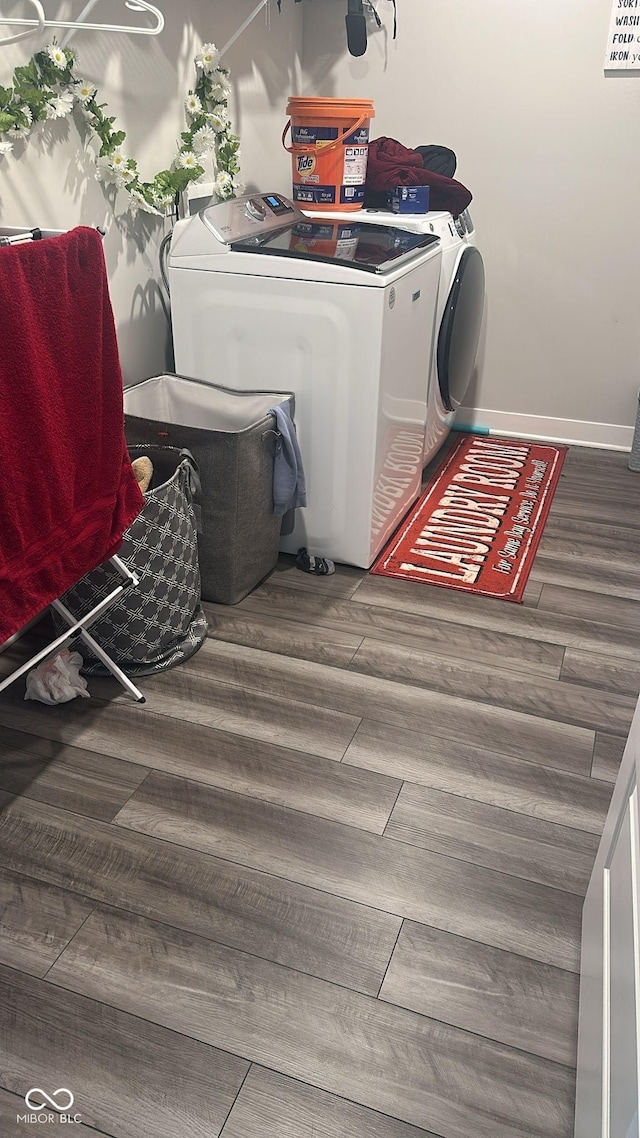 laundry area with laundry area, wood finished floors, baseboards, and washer and clothes dryer