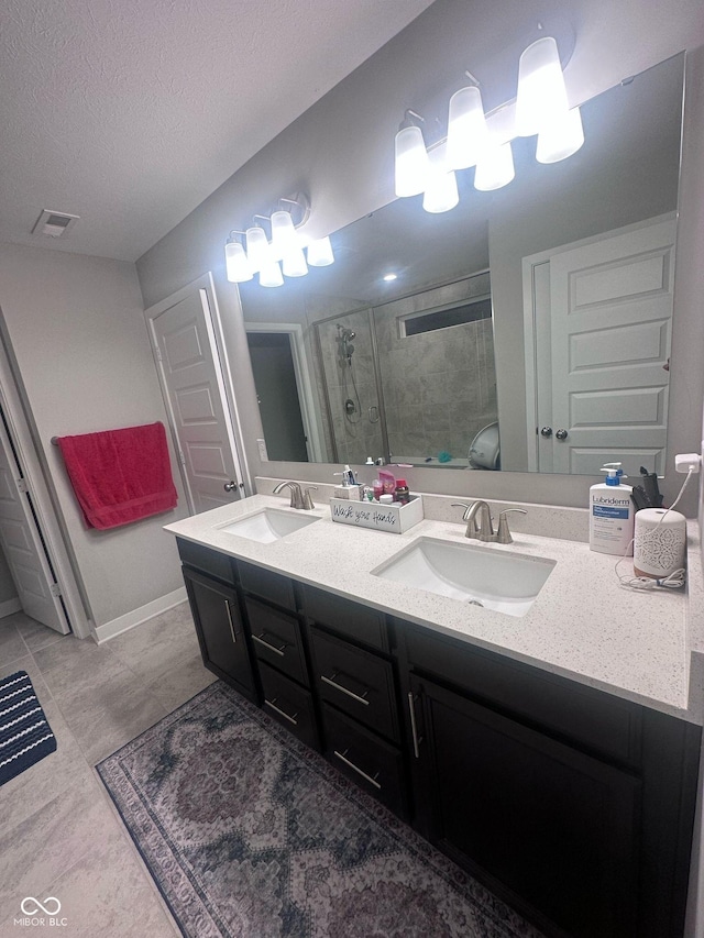 full bathroom with a textured ceiling, double vanity, a stall shower, and a sink