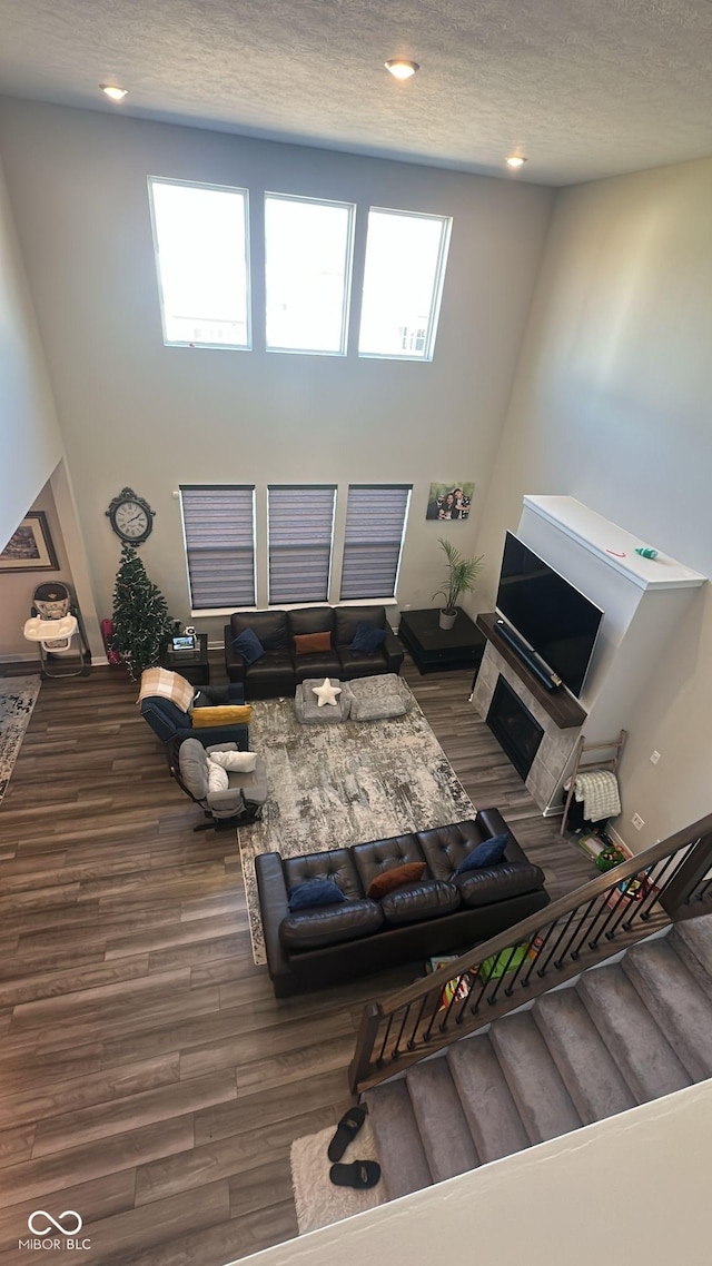 living area with stairway, a high ceiling, wood finished floors, and a textured ceiling