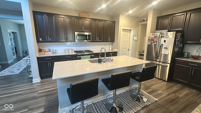 kitchen with a sink, tasteful backsplash, appliances with stainless steel finishes, and dark wood-style floors