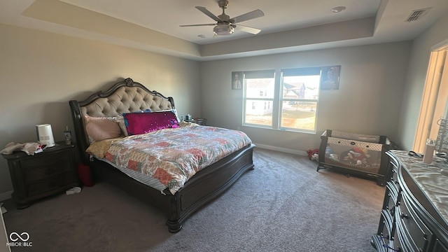 bedroom with a raised ceiling, carpet flooring, baseboards, and visible vents