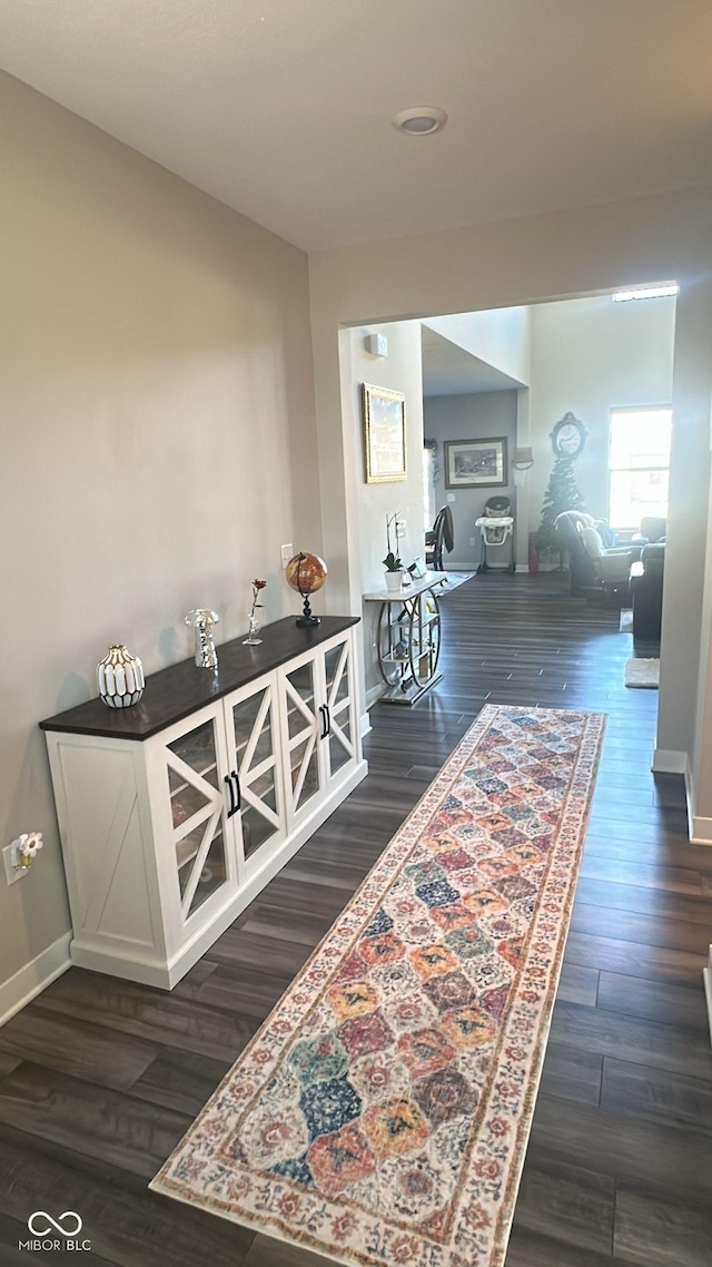 corridor with dark wood-style floors and baseboards