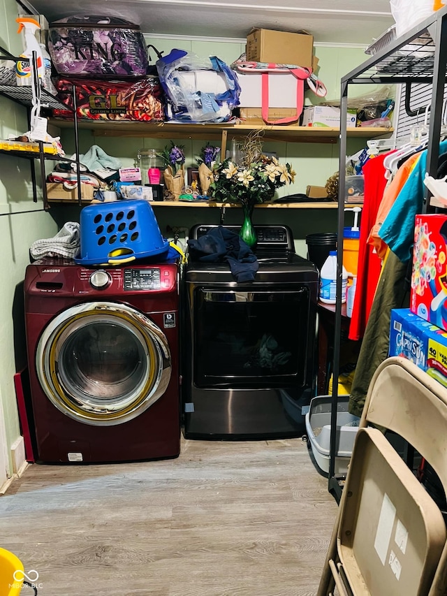 clothes washing area featuring wood finished floors, washing machine and dryer, and laundry area