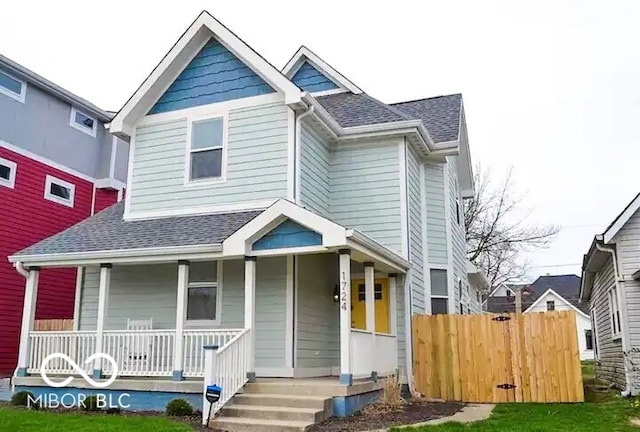 view of front of home featuring covered porch, fence, and roof with shingles