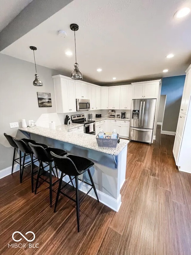 kitchen with stainless steel appliances, white cabinets, a peninsula, and dark wood-style floors