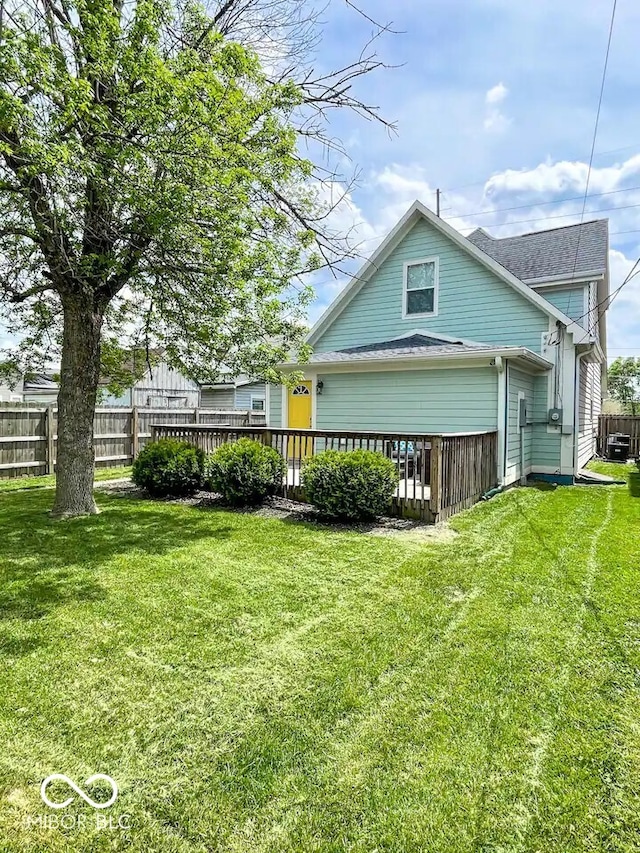 back of property featuring fence, a deck, and a yard