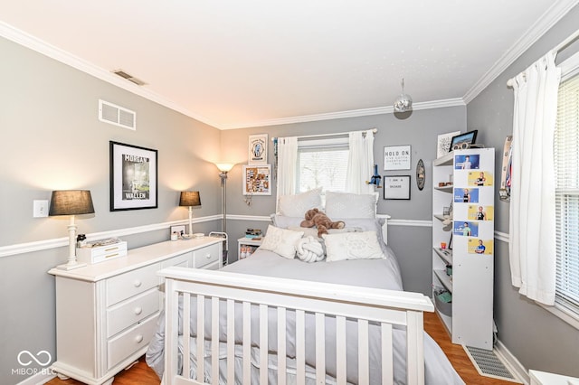 bedroom featuring light wood finished floors, visible vents, and crown molding