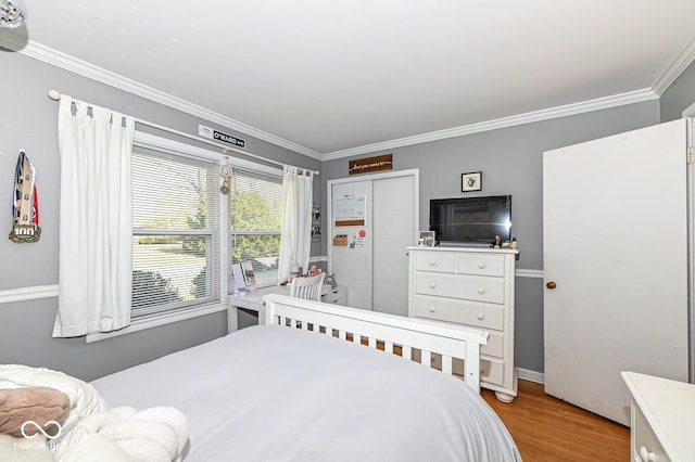 bedroom with crown molding, light wood-style flooring, and a closet