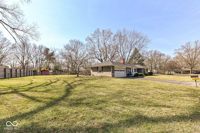 view of yard with aphalt driveway, an attached garage, and fence