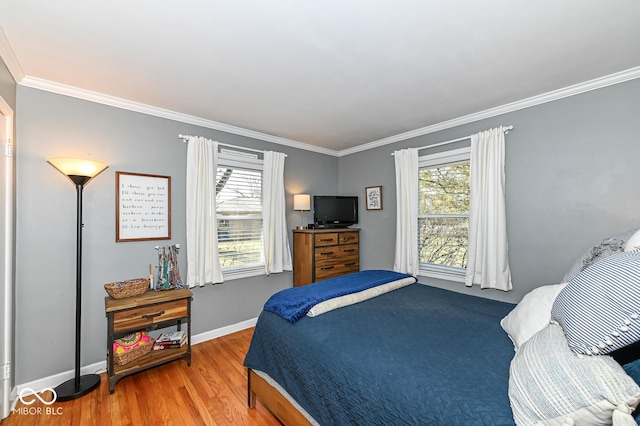 bedroom featuring multiple windows, wood finished floors, baseboards, and ornamental molding