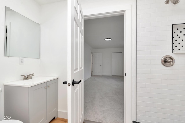 bathroom featuring tiled shower, vanity, and baseboards