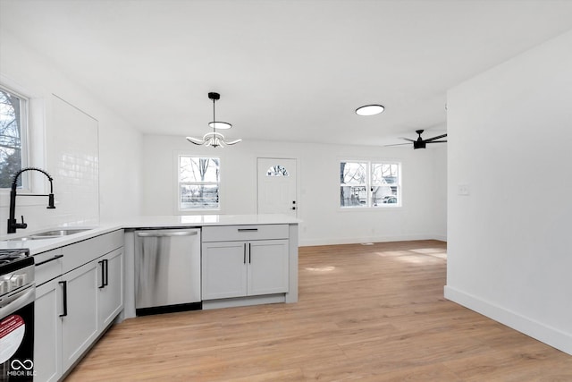 kitchen with appliances with stainless steel finishes, light wood-type flooring, a sink, and a wealth of natural light