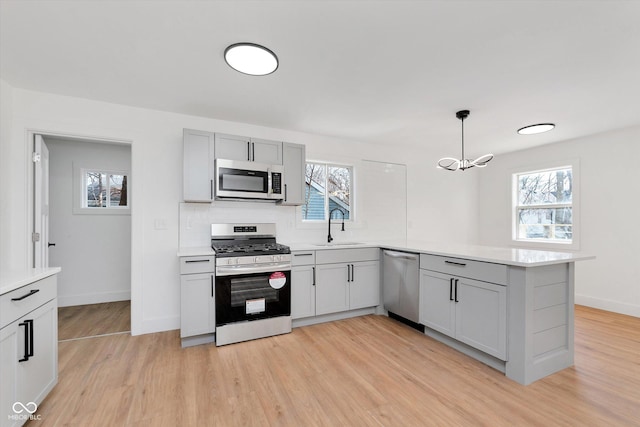 kitchen featuring stainless steel appliances, light wood-type flooring, light countertops, and a sink