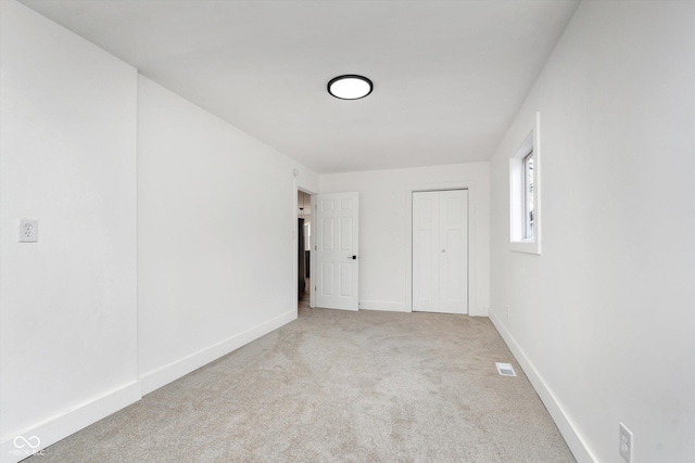 unfurnished bedroom with a closet, carpet flooring, visible vents, and baseboards