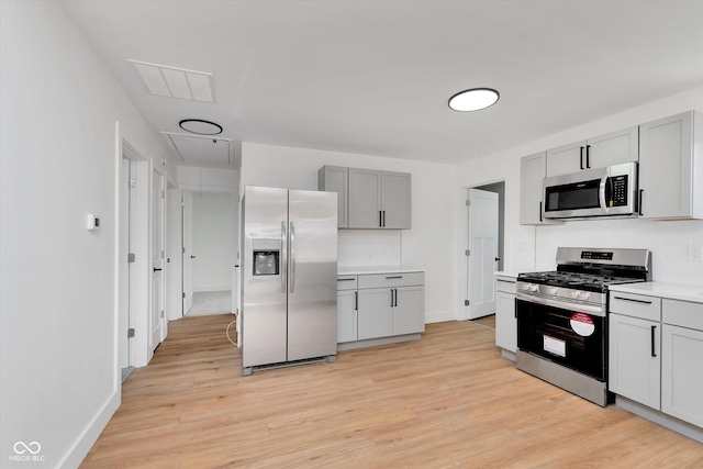 kitchen with stainless steel appliances, light wood-type flooring, gray cabinets, and light countertops