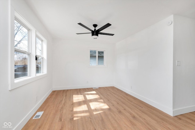 empty room with light wood-style flooring, visible vents, ceiling fan, and baseboards