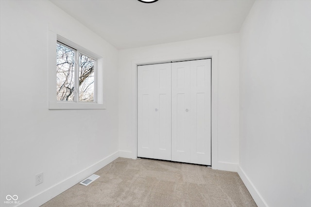 unfurnished bedroom with a closet, carpet, visible vents, and baseboards