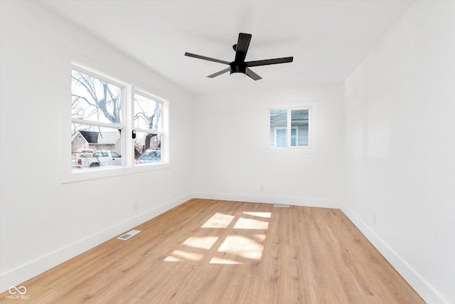 unfurnished room featuring a ceiling fan, visible vents, light wood-style flooring, and baseboards