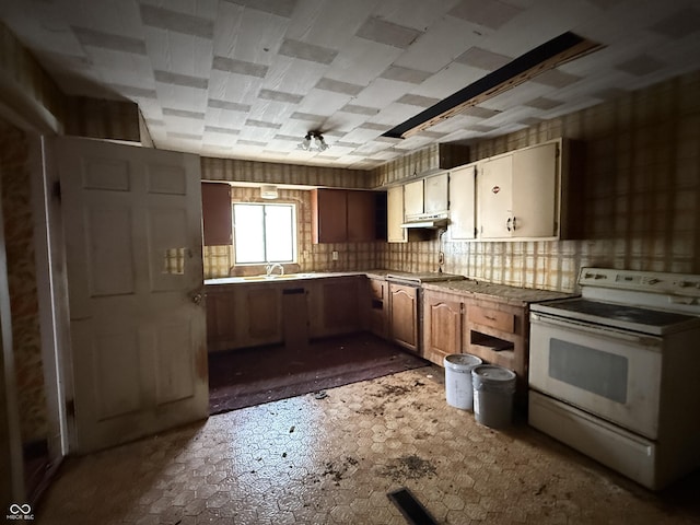 kitchen featuring white range with electric cooktop, tasteful backsplash, light countertops, and a sink