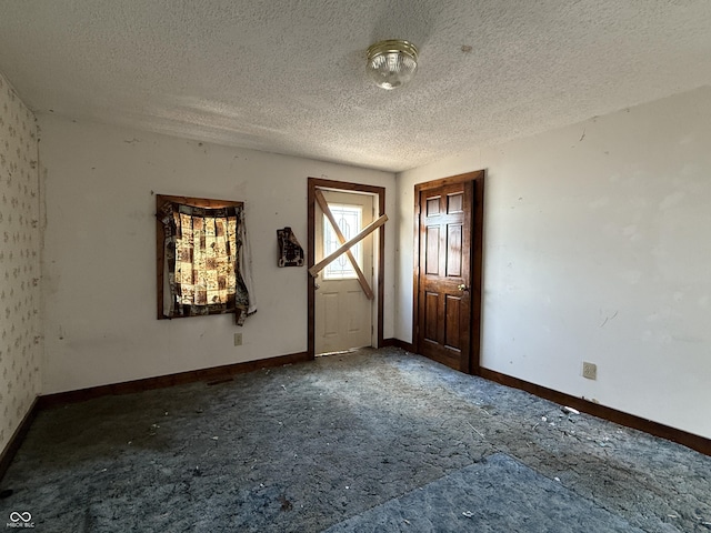 spare room with a textured ceiling and baseboards