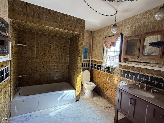 bathroom with vanity, tile walls, toilet, and bathing tub / shower combination