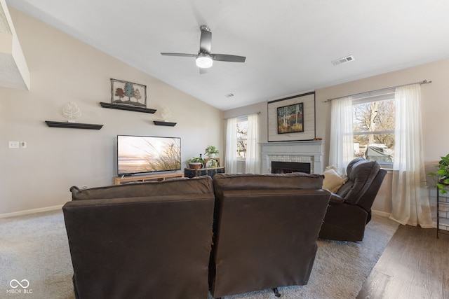 living area featuring a ceiling fan, baseboards, visible vents, vaulted ceiling, and a brick fireplace