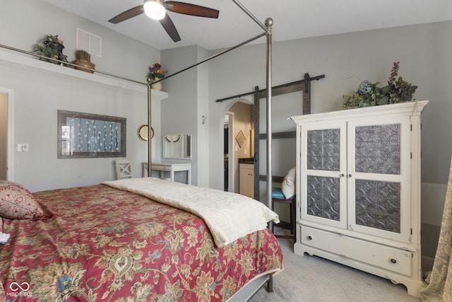 carpeted bedroom featuring visible vents, arched walkways, ceiling fan, and a barn door