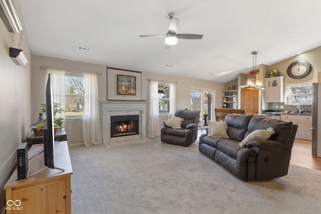 living room with visible vents, plenty of natural light, a fireplace, and vaulted ceiling