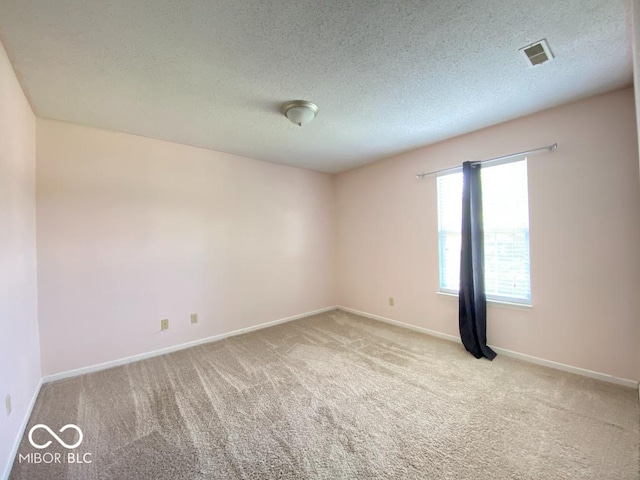 unfurnished room featuring carpet floors, visible vents, a textured ceiling, and baseboards