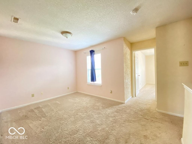 unfurnished room with light carpet, baseboards, and a textured ceiling